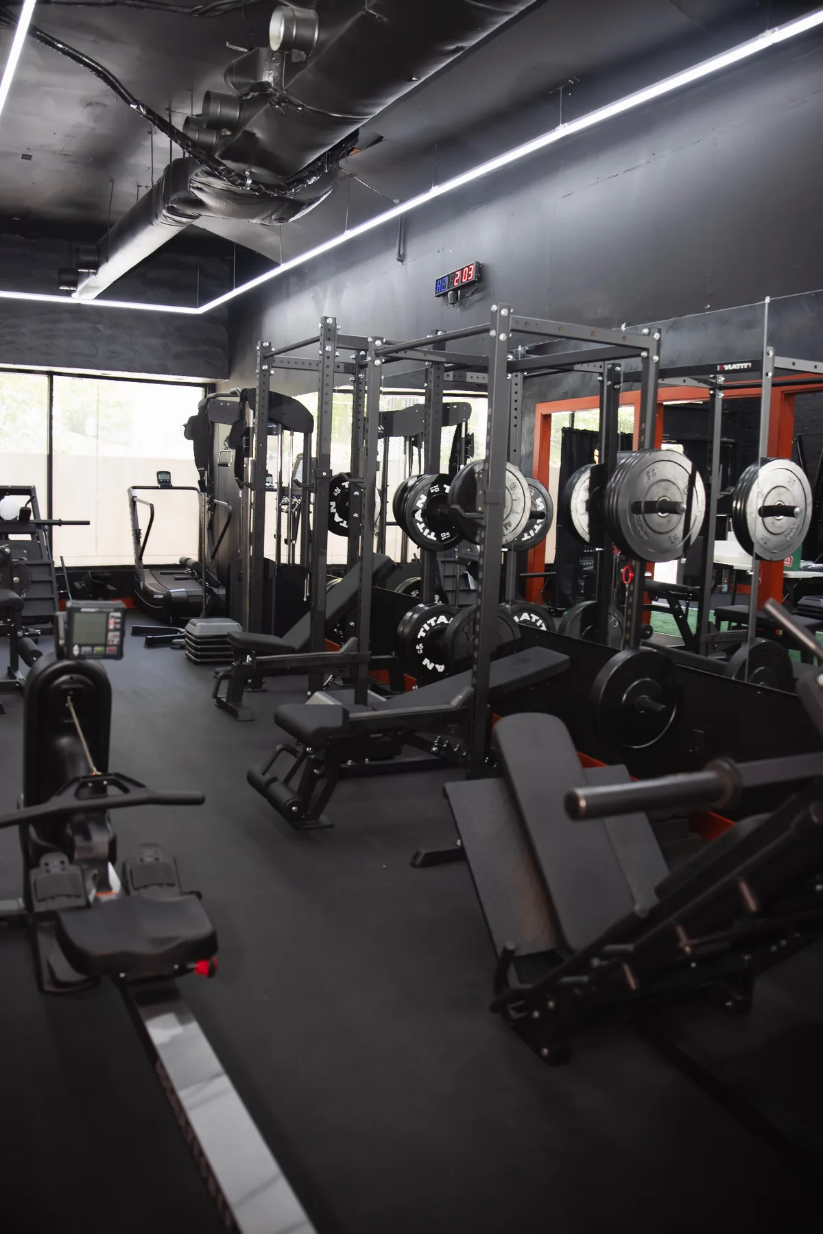 Squat racks and benches under strip lights at Body Built By You